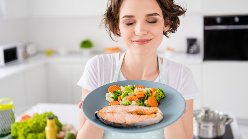 femme avec assiette de saumon et légumes